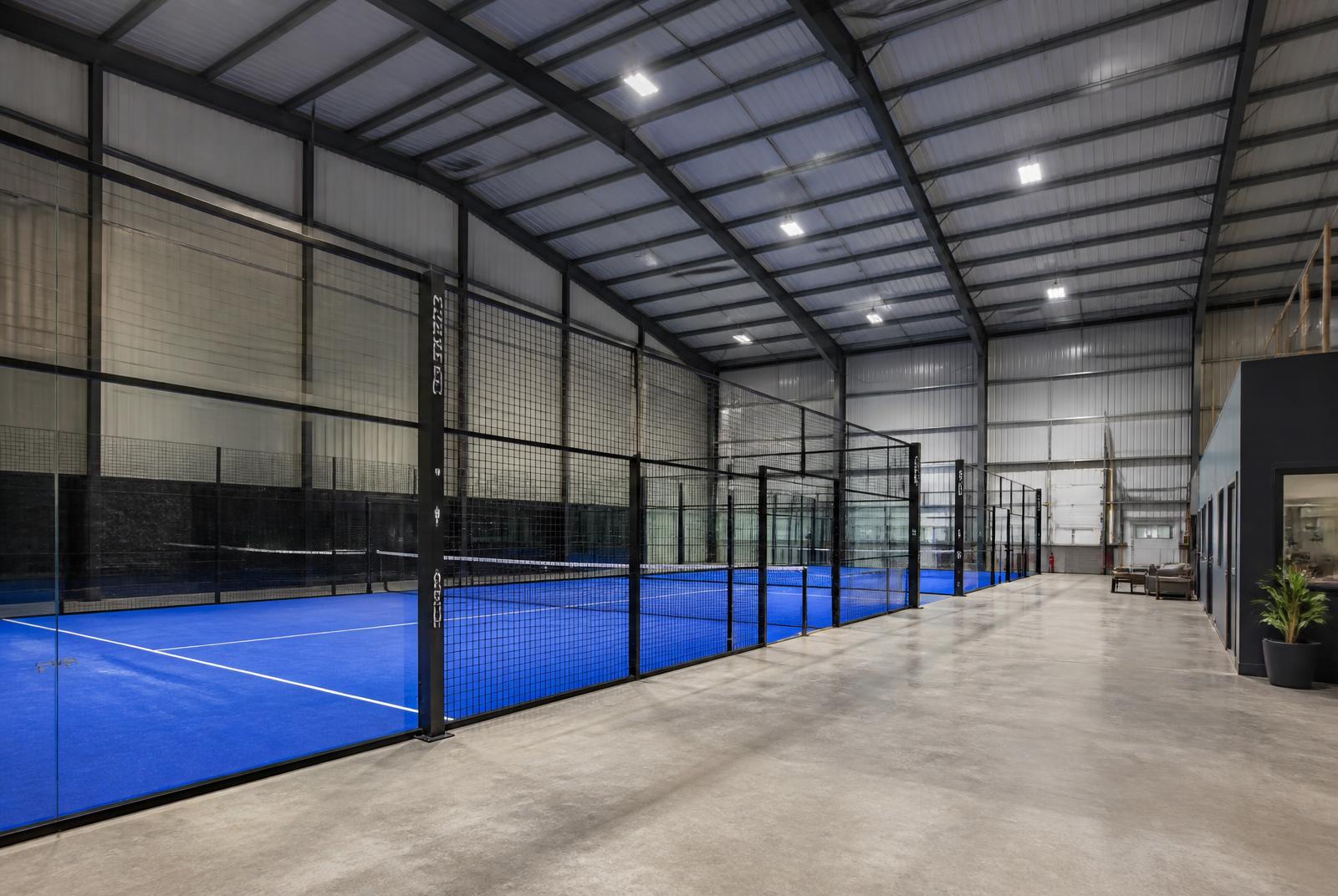 Indoor padel courts inside a converted UK warehouse with a steel portal frame